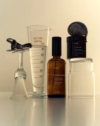 Klur skincare bottles arranged alongside laboratory glassware and a seashell on a glossy white surface