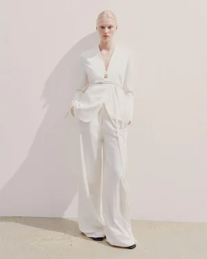Model wearing a tailored white suit with a tied belt standing against a seamless background for the Joseph Spring Summer 2025 lookbook.
