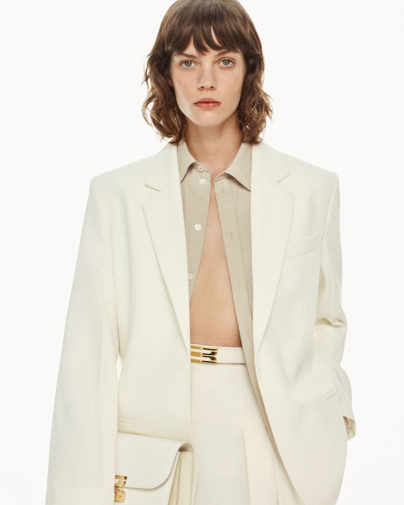 Model with brown hair wearing a white blazer and matching trousers for Victoria Beckham Pre-Fall 2025