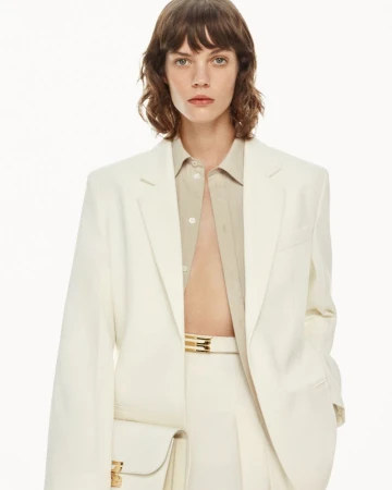Model with brown hair wearing a white blazer and matching trousers for Victoria Beckham Pre-Fall 2025