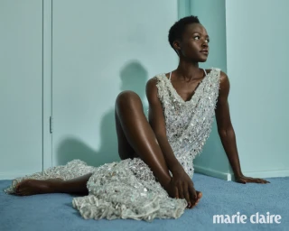Lupita Nyong'o wearing a white embellished dress sitting on a blue carpet against a light blue wall for Marie Claire Australia.