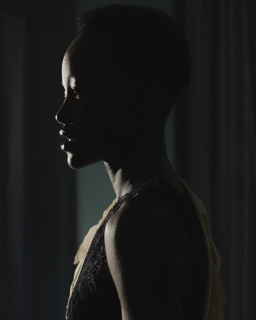 Profile portrait of Lupita Nyong'o in dramatic low-key lighting for Marie Claire Australia, captured by Robin Harper.