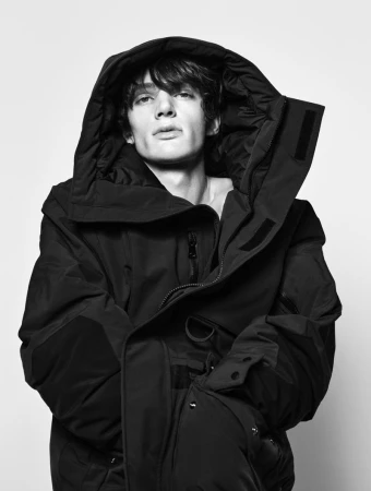 Model wearing a heavy black hooded parka jacket against a plain white background for Zara Origins Drop III