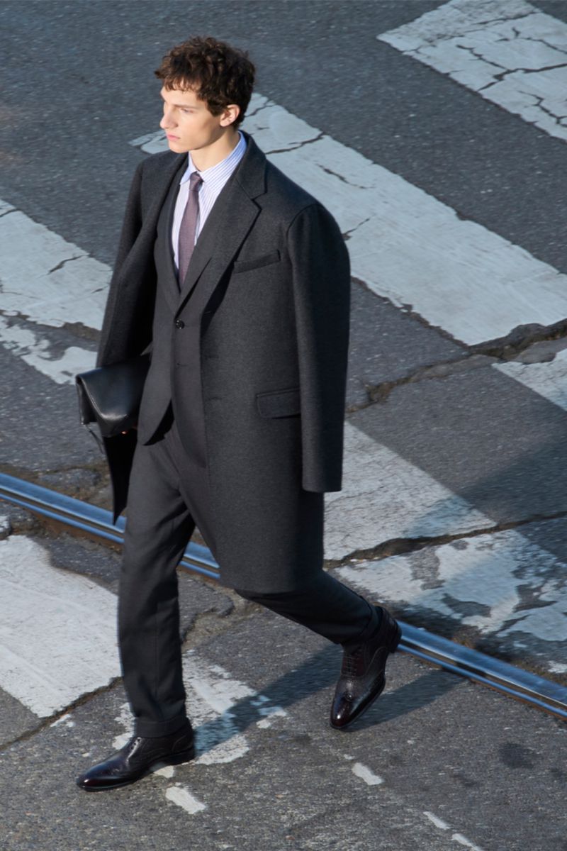 Fashionable man in a dark suit walks across a city crosswalk with confident stride and blurred motion, capturing urban style and elegance.