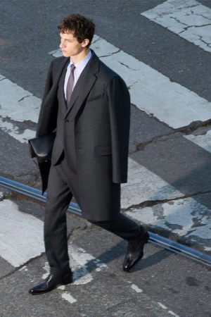 Fashionable man in a dark suit walks across a city crosswalk with confident stride and blurred motion, capturing urban style and elegance.