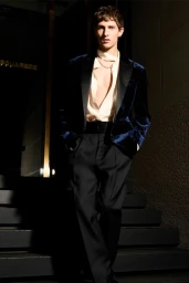 Male model in a blue velvet blazer and dark trousers descending exterior stone steps at night