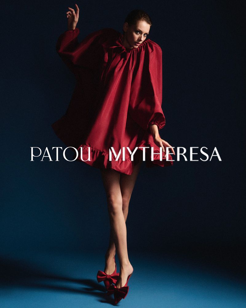 Fashion shot of a woman in a red dress and matching bow shoes against a blue backdrop, showcasing a stylish and elegant attire.