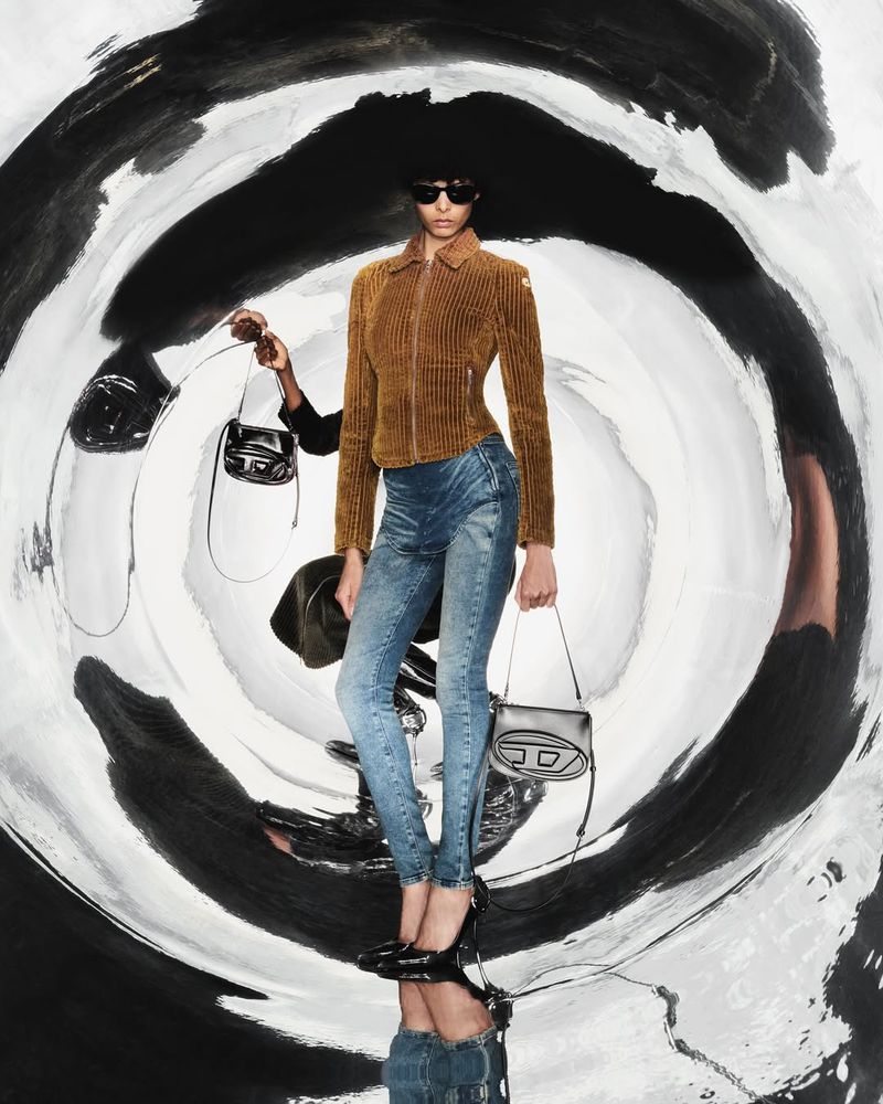 Fashion shot of a woman in denim and a brown corduroy jacket, holding a small black purse against a distorted, abstract background.