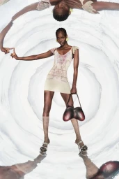Model in printed mini dress holding a handbag against a swirling circular background pattern