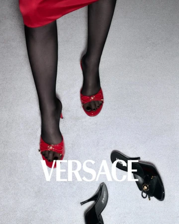 Fashion still life features a model wearing red mules and black stockings, with other black mules arranged on a gray backdrop.