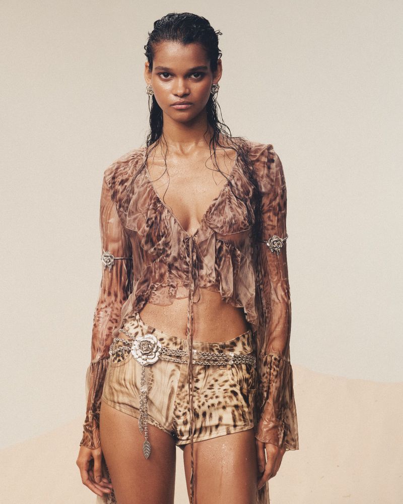 A woman poses in a sheer top and shorts with an animal print design. Silver jewelry and wet-look hair complete the fashion shot.