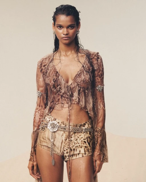 A woman poses in a sheer top and shorts with an animal print design. Silver jewelry and wet-look hair complete the fashion shot.