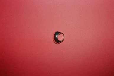 Silver sculptural ring displayed against a solid pink textured backdrop