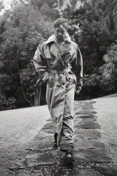 Chris Hemsworth walking outdoors on a stone path wearing an oversized belted trench coat for Sharp Magazine.
