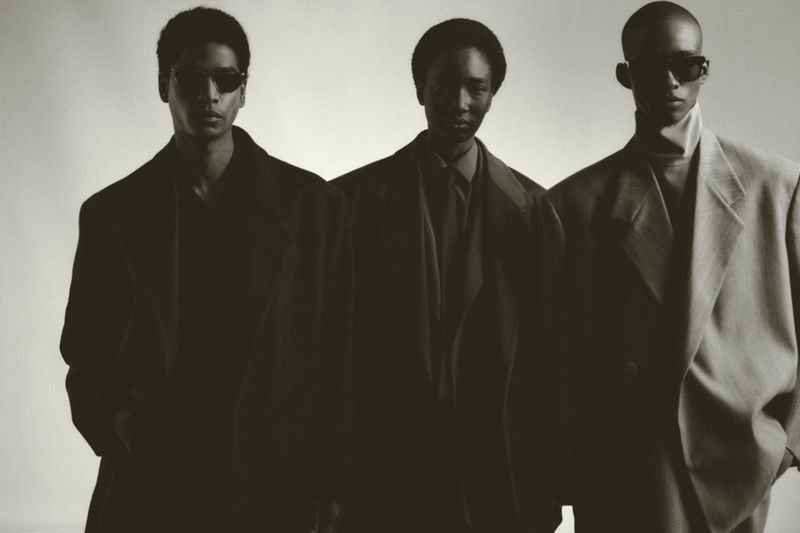 Three male models in tailored blazers and sunglasses posing against a plain light background for Fear of God.