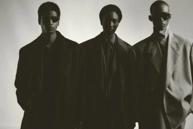 Three male models in tailored blazers and sunglasses posing against a plain light background for Fear of God.