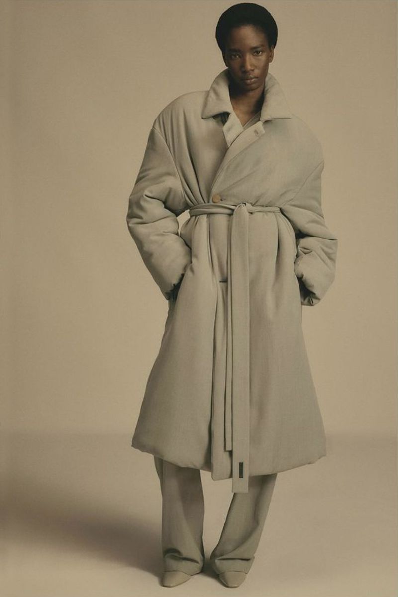 Model wearing an oversized beige puffer coat with a matching tie belt against a neutral background