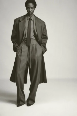Model wearing an oversized suit and tie against a plain light studio background for Fear of God