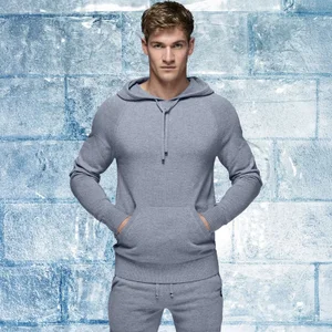Model Matty Carrington wears a grey knit hoodie and matching sweatpants against an ice brick backdrop for Ron Dorff AW24.