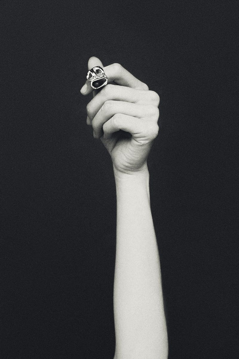 Elegant ring on a woman's hand against a dark backdrop, creating a sophisticated and minimalist jewelry advertisement with focus on the accessory.