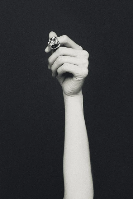 Elegant ring on a woman's hand against a dark backdrop, creating a sophisticated and minimalist jewelry advertisement with focus on the accessory.