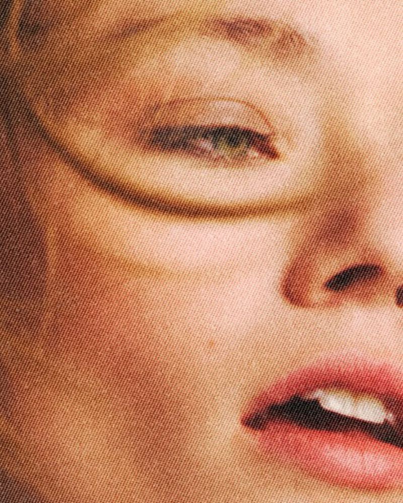 Close-up portrait of a woman's face with her eyes closed, focusing on her features, skin texture, and soft lighting in a beauty context.