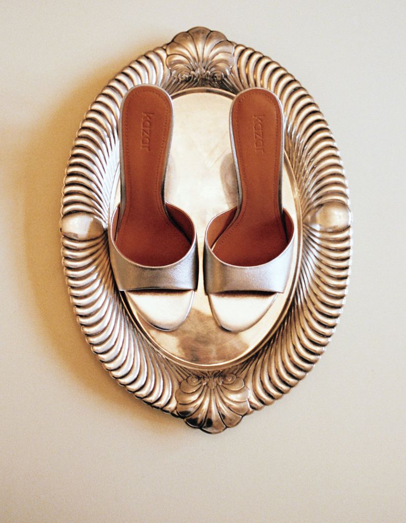 Elegant silver heeled mules displayed on an ornate silver tray, showcasing a blend of fashion and vintage aesthetics.