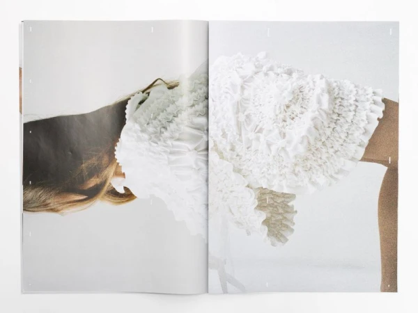 Woman wearing white textured mini dress in fashion editorial with a white background photographed with soft diffused lighting.