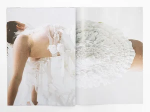 Model wearing a white ruffled textured dress against a bright white background in an editorial spread