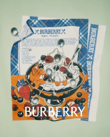Stylized product shot of a Burberry kitchen towel with an illustration of an Eton Mess dessert, berries, whipped cream, spoons, and Burberry logos.