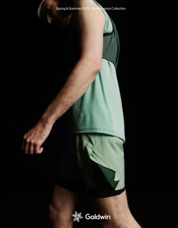 Athletic male in workout gear poses against a dark background, showcasing a light green sleeveless top and matching shorts for activewear fashion.