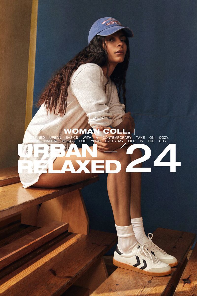 Model wearing a grey sweatshirt, blue baseball cap, and sneakers, seated on wooden steps for Lefties urban relaxed 24 campaign