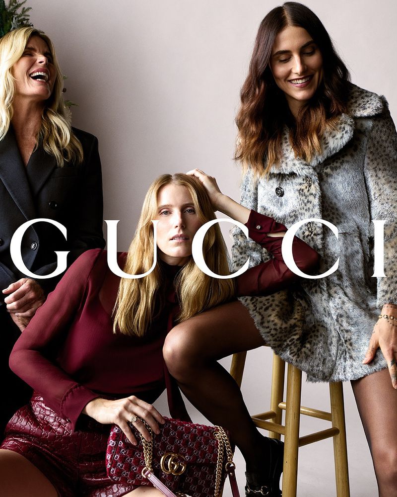 Three fashionable adult women pose indoors, modeling outfits and accessories from Gucci's latest collection, captured in a medium shot.