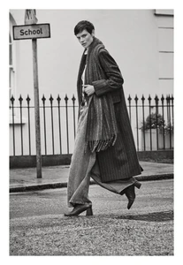 Model Saskia de Brauw walking on a city street wearing a long striped coat, scarf, and wide trousers for ME+EM.