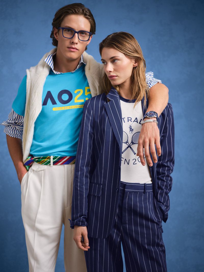 Two models pose in Ralph Lauren tennis apparel against a blue backdrop, showcasing a blazer, polo shirt, and coordinated sporty fashion.