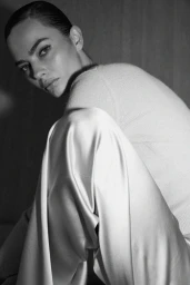 Black and white portrait of model Moa Aberg seated in a knit sweater and draped satin trousers for Éterne.