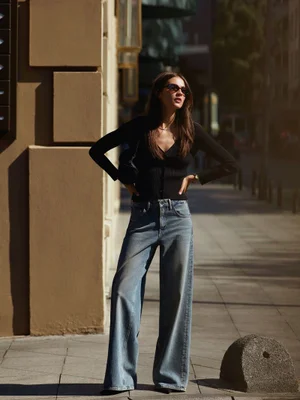 Model in dark top and blue jeans posing on a sunny city sidewalk for Mavi Back To City campaign