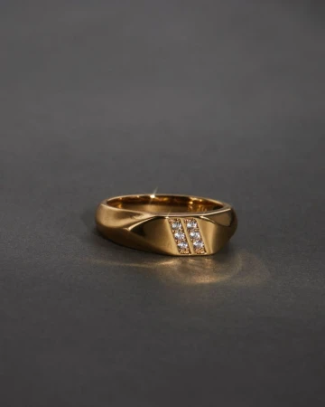 Close-up studio shot of a gold ring with diamonds. The ring is centered and well-lit against a dark gray background.