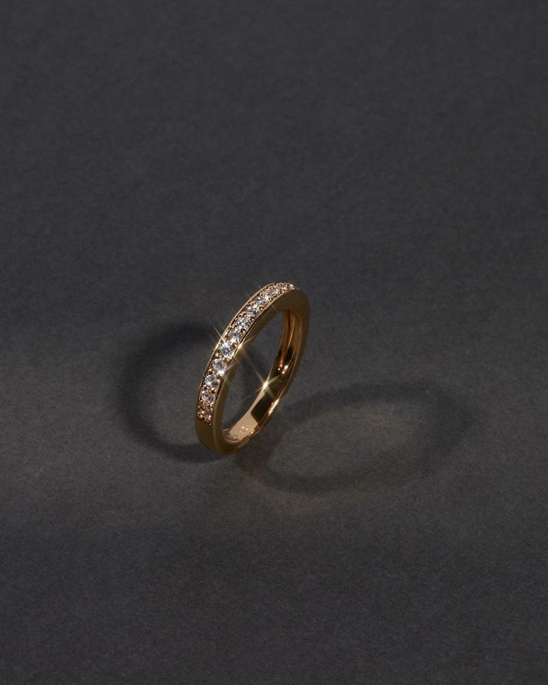 Close-up studio shot of an ornate gold ring adorned with diamonds, showcased against a dark gray background with subtle studio lighting.