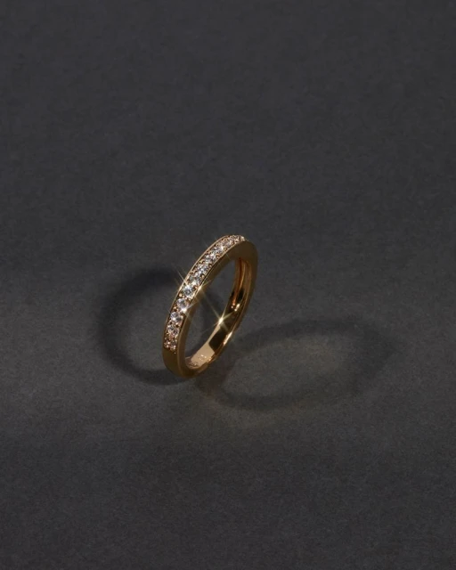 Close-up studio shot of an ornate gold ring adorned with diamonds, showcased against a dark gray background with subtle studio lighting.