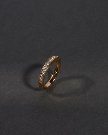 Close-up studio shot of an ornate gold ring adorned with diamonds, showcased against a dark gray background with subtle studio lighting.