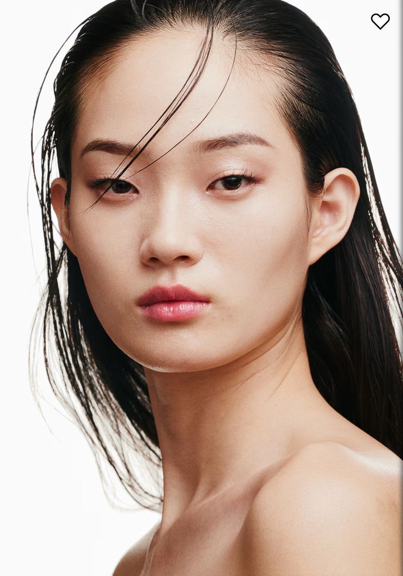 Close-up portrait of an East Asian adult woman with slicked-back black hair, smooth skin, pink lips, and a neutral expression on a bright white background.