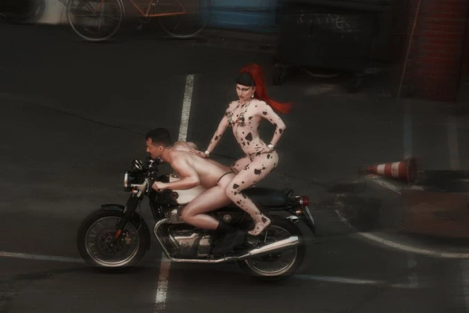 Two people on a motorcycle on a dark asphalt road. The woman wears a spotted bodysuit with red hair. A vintage bicycle is visible.