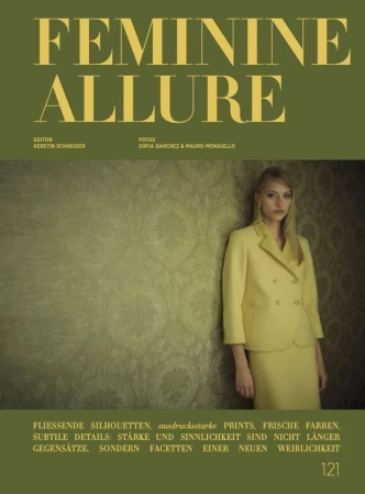 Editorial fashion cover featuring a blonde model in a yellow suit, set against a textured wall with olive green background and prominent typography.