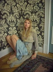Blonde female model seated on the floor against a patterned damask wallpaper background for Harper's Bazaar Germany