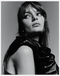 Portrait of a woman with dark hair wearing a black top against a solid grey background for H&M tailoring holiday.
