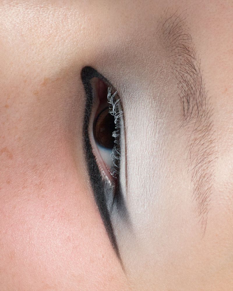 Close-up of an adult female eye with heavy black eyeliner and light eyeshadow. Focus on the eye and makeup details.
