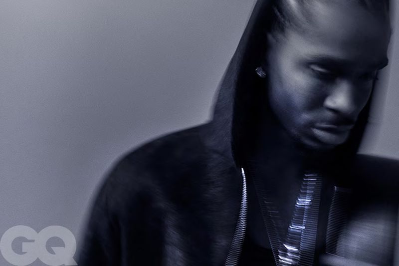 Portrait of a man in a hoodie, wearing a chain necklace. The image is in blue tones with the GQ logo in the bottom left corner.