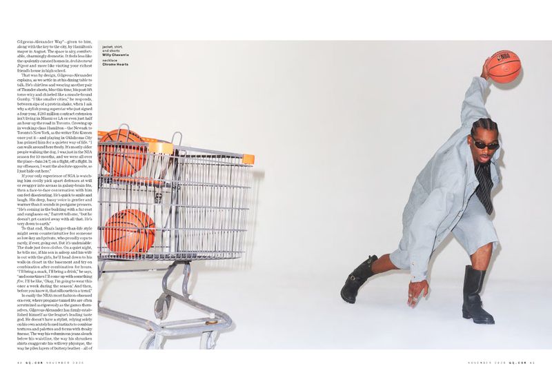 Editorial fashion shot of an adult male in a light grey suit and black boots holding a basketball, posed next to a shopping cart.