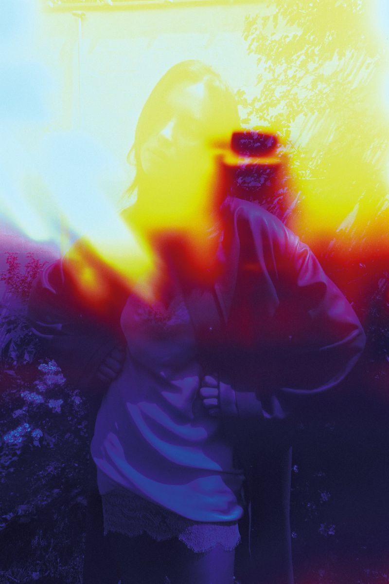 Model Irina Shayk standing with hands on hips enveloped in heavy yellow and red film light leaks for Self Service.